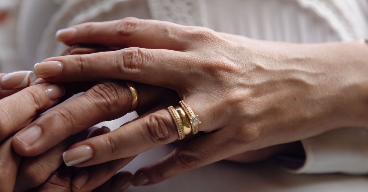 Intimate close-up of a couple holding hands displaying their wedding rings, symbolizing love and unity.